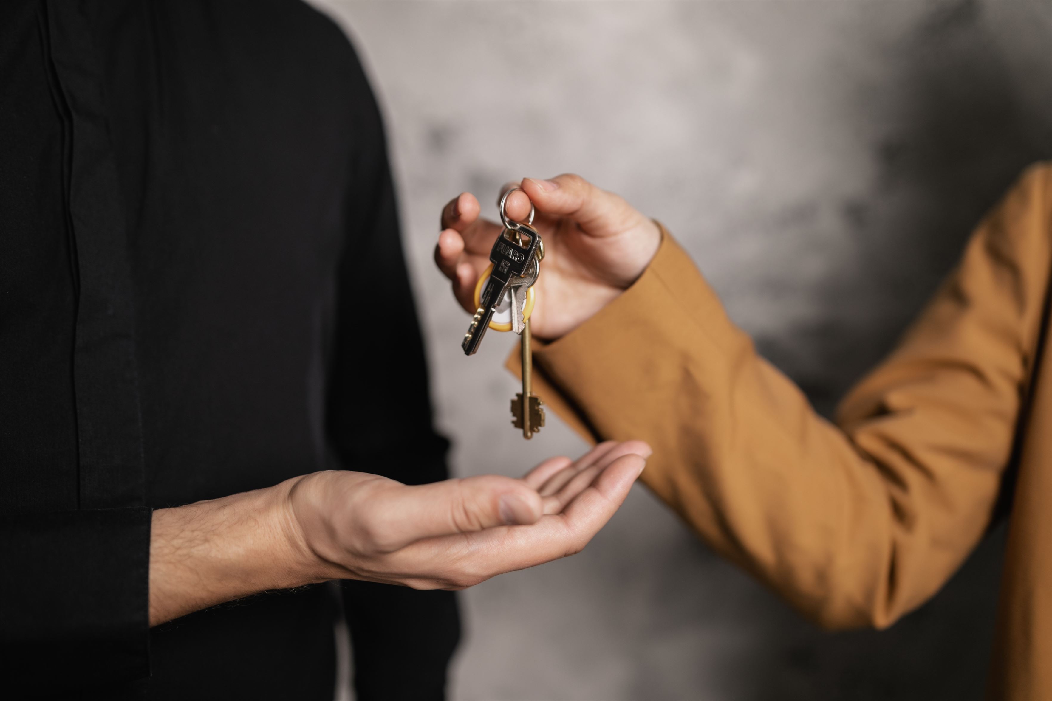 Person handing off keys to other person.