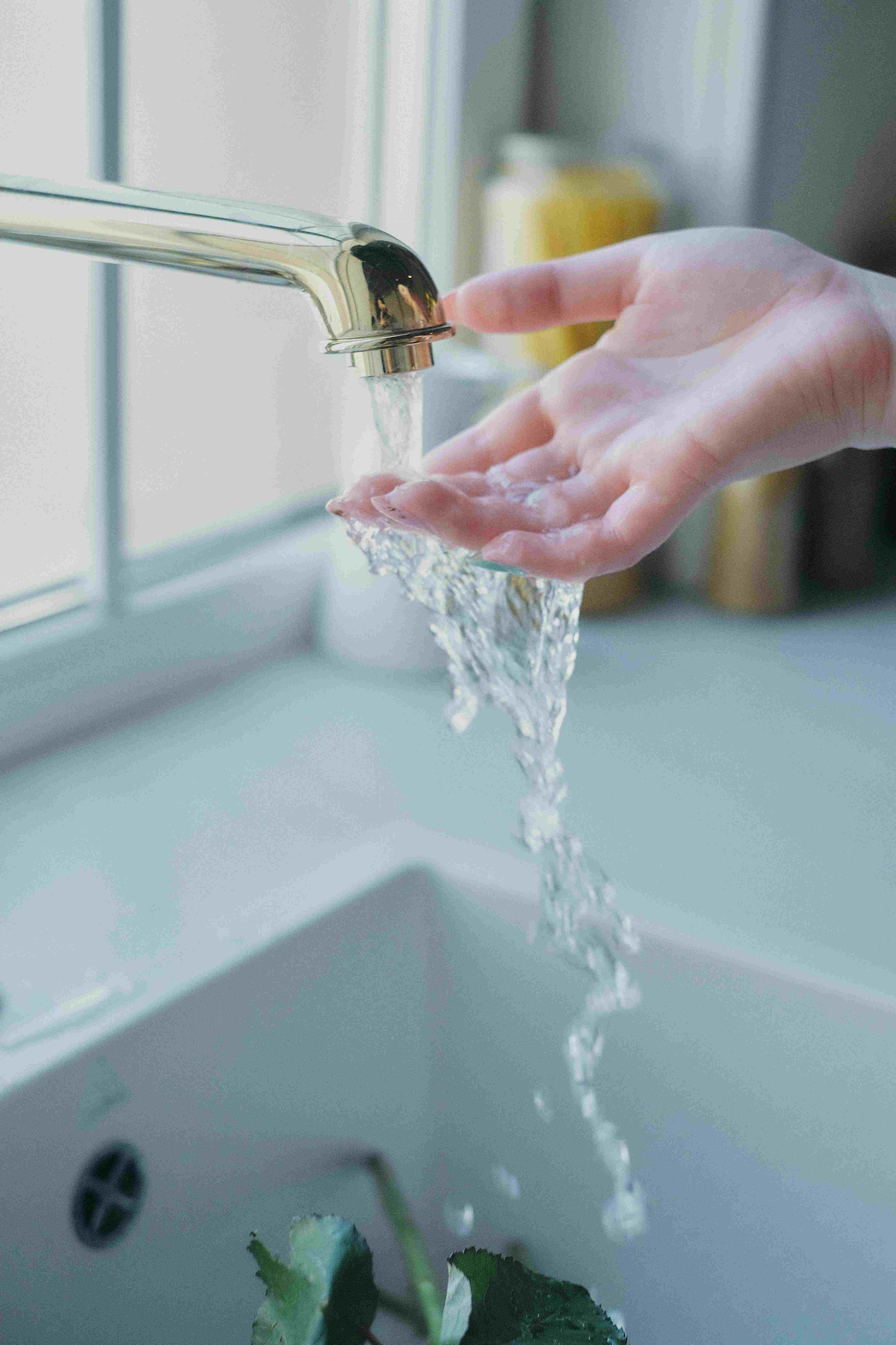 Water running through a woman's hand at a sink.